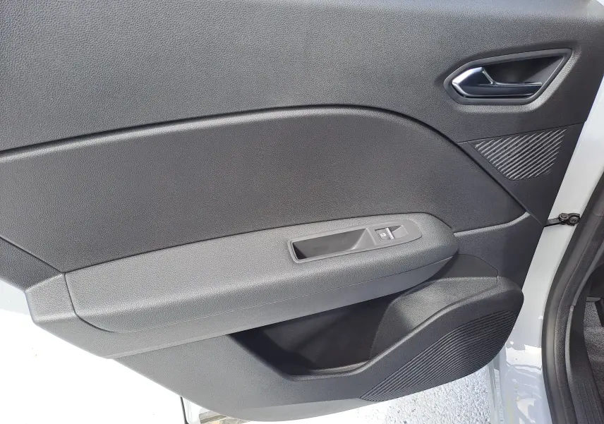 Intérieur de la porte côté gauche du Renault Captur gris Rafale 2025, avec commandes de fenêtre et poignée noire.