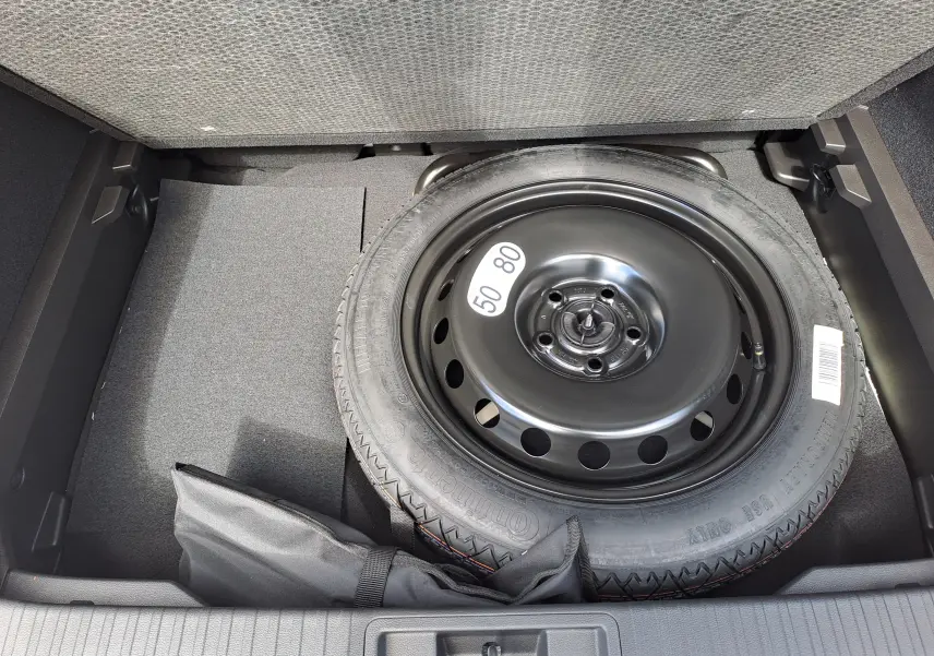 Roue de secours noire dans le coffre du Renault Captur 2025 gris Rafale métal avec toit noir.