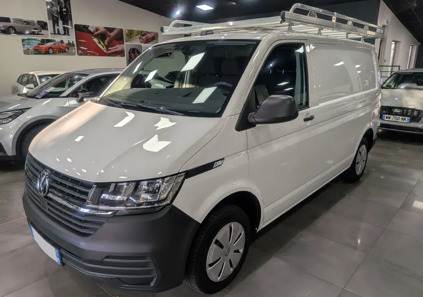 Volkswagen Transporter 6.1 blanc Candy en 3/4 avant droit avec galerie de toit en intérieur showroom.