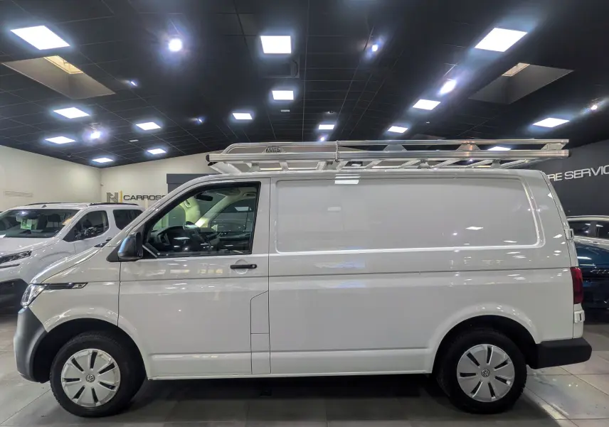 Vue de profil côté gauche d'un Volkswagen Transporter 6.1 Van blanc Candy avec galerie de toit en intérieur showroom.