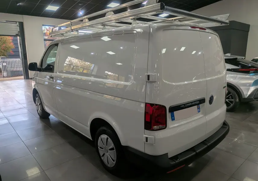 Vue 3/4 arrière droite du Volkswagen Transporter 6.1 Van blanc Candy avec galerie de toit métallique en intérieur showroom.
