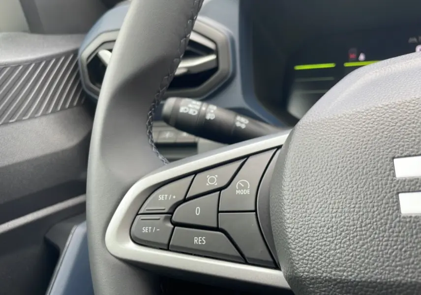 Gros plan sur le volant cuir gris du Dacia Bigster 2025, avec commandes intégrées au volant côté gauche.