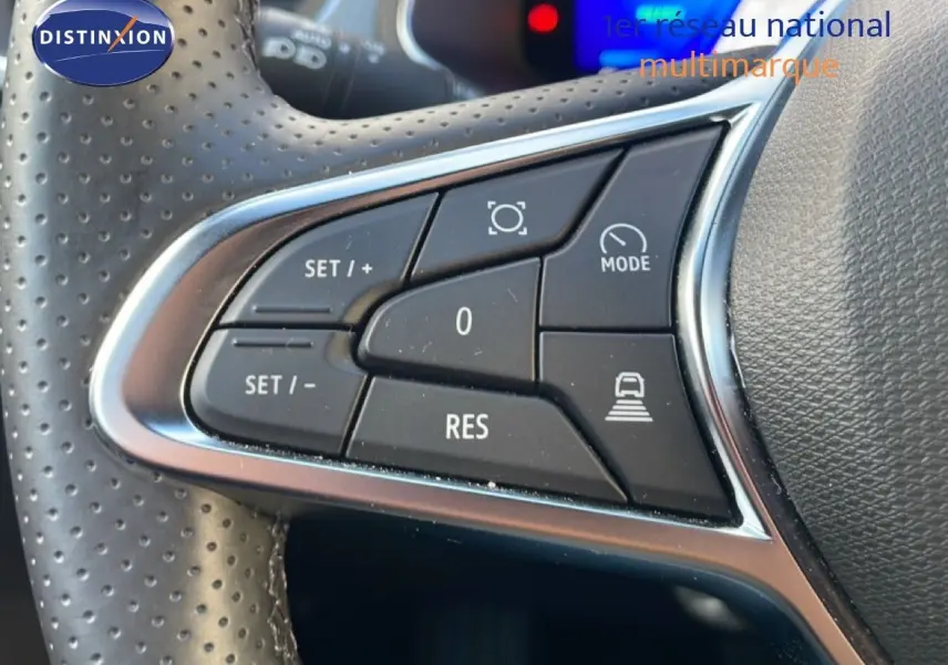 Gros plan sur les commandes au volant en cuir perforé du Renault Symbioz gris Cassiopée, mettant en avant les boutons de régulateur et mode conduite.