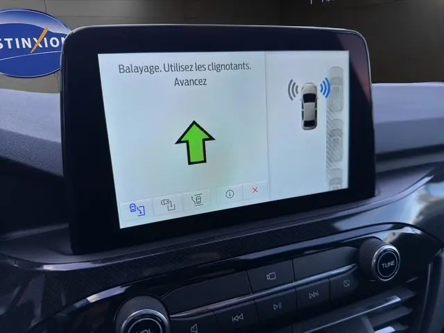 Écran central du tableau de bord du Ford Kuga 2024 montrant l'aide au stationnement avec instructions en français.