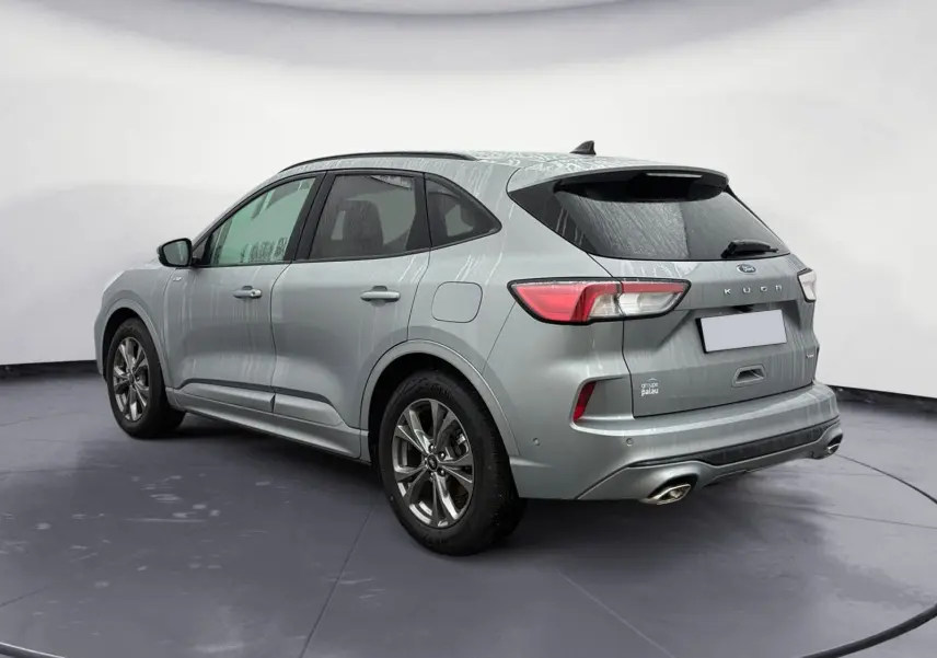 Vue 3/4 arrière droite d’un Ford Kuga gris 2024 hybride essence, finition ST-Line X avec double sortie d’échappement.