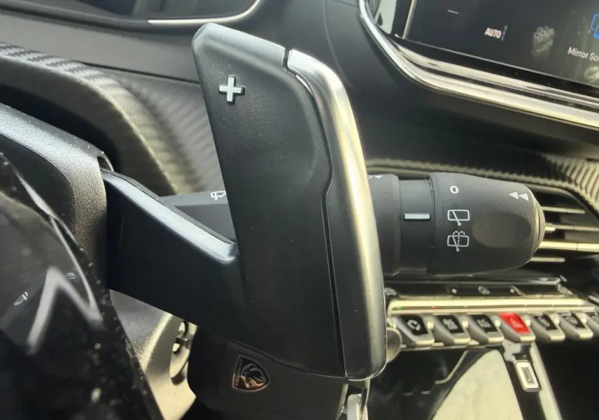 Gros plan sur la commande de palette de changement de vitesse côté droit dans l’habitacle gris de la Peugeot 208 Hybrid 110 e-DCS6 Allure.