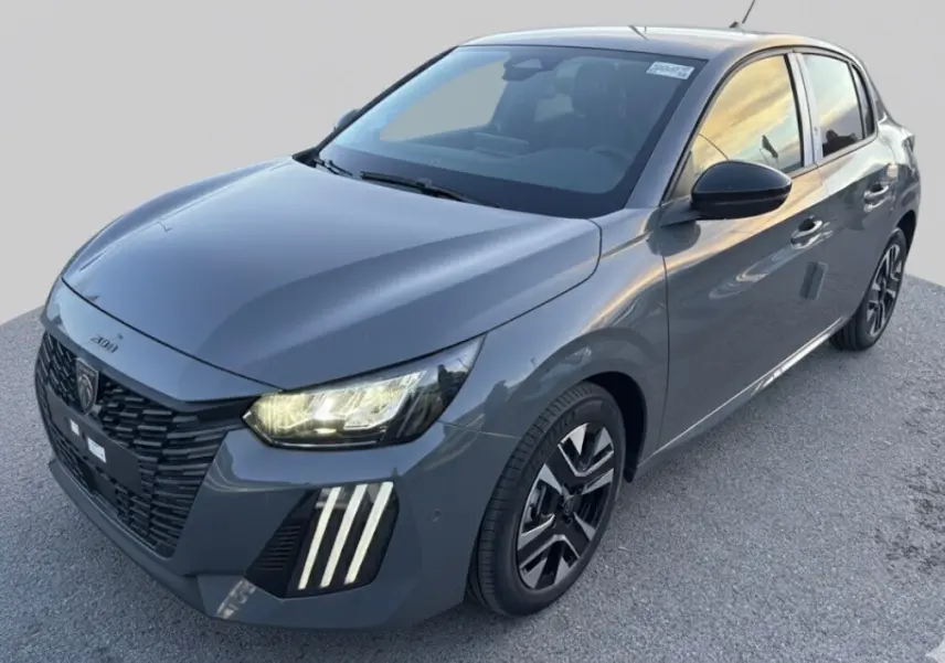 Peugeot 208 Hybrid gris vue 3/4 avant droit, avec feux allumés et jantes alliage noires et argentées.