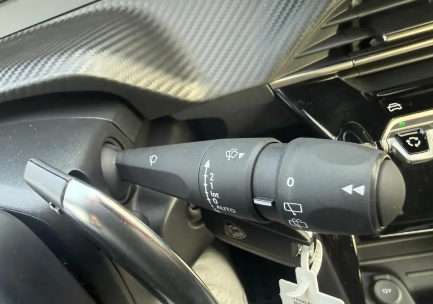 Gros plan sur la commande des essuie-glaces du Peugeot 208 Hybrid 110 gris, côté gauche du volant.