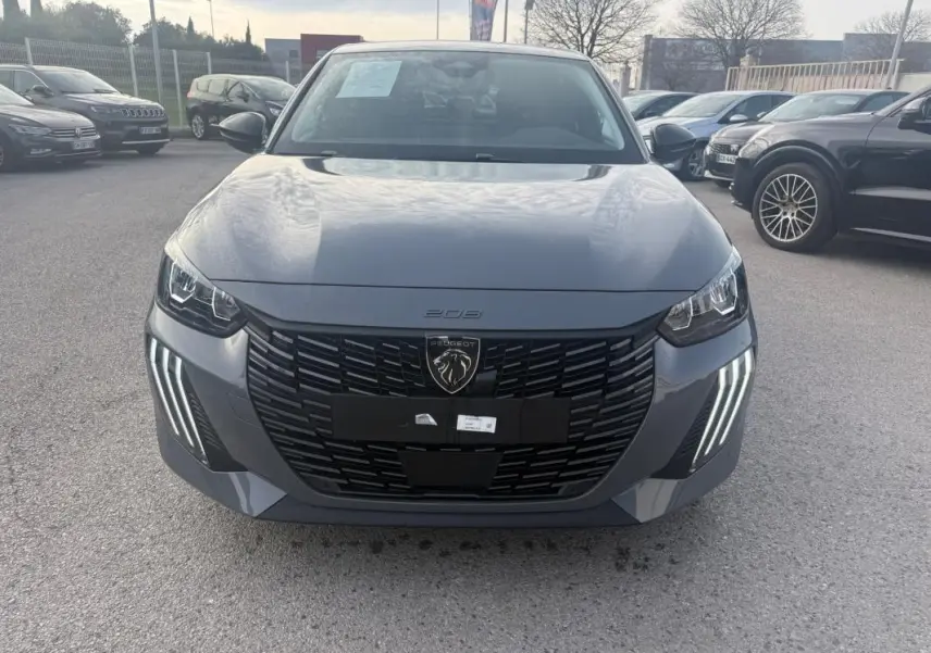 Vue avant d'une Peugeot 208 Hybrid 110 gris, avec sa calandre noire et ses feux diurnes à LED en griffes distinctives.