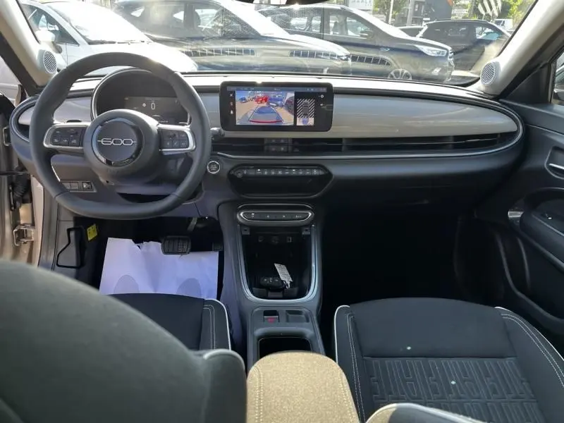 Vue intérieure avant du Fiat 600 T-Gen 3 beige 2025, tableau de bord épuré avec écran central et volant multifonction.