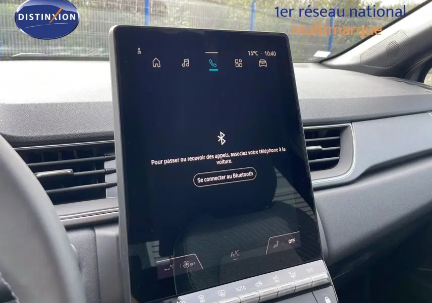 Écran tactile central allumé dans l’habitacle gris du Renault Captur 2025, version hybride 3/4 avant droit.