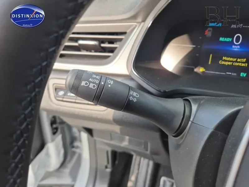 Gros plan sur la commande des phares à gauche du volant dans l'habitacle gris du Renault Captur 2025 hybride.