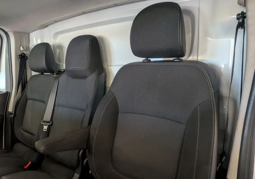 Gros plan sur les sièges avant en tissu noir du Renault Trafic Fourgon blanc Glacier, version L2H2 Grand Confort 2021.
