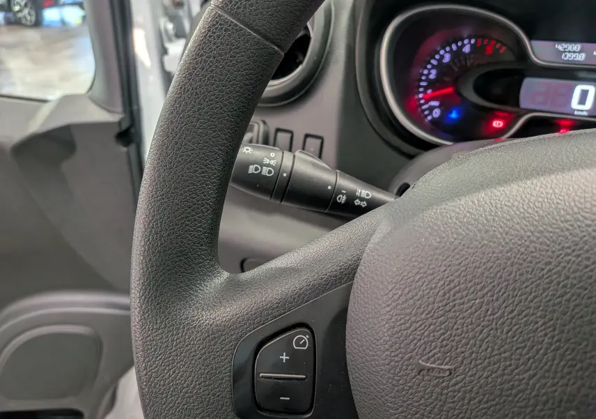 Gros plan sur le volant noir et le tableau de bord éclairé du Renault Trafic Fourgon blanc Glacier, version 2021.