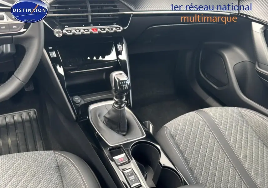 Intérieur Peugeot 2008 1.2 100 allure 2025, vue sur la console centrale avec levier de vitesse manuel et sièges tissu gris.