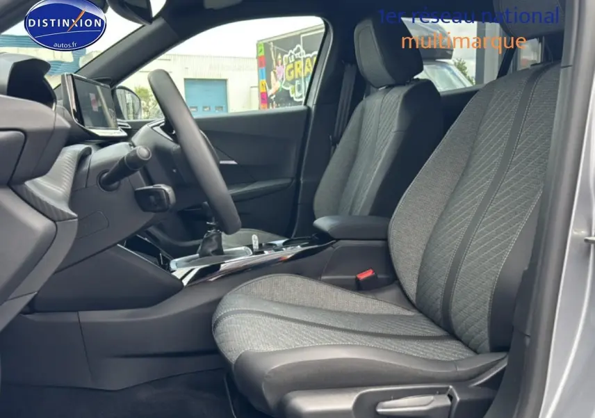 Vue intérieure côté conducteur du Peugeot 2008 gris artense, mettant en valeur les sièges en tissu et la console centrale.