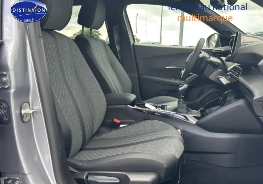 Vue intérieure côté conducteur du Peugeot 2008 gris artense 2025, montrant les sièges en tissu casual lomsa embossé et la console centrale avec boîte manuelle.
