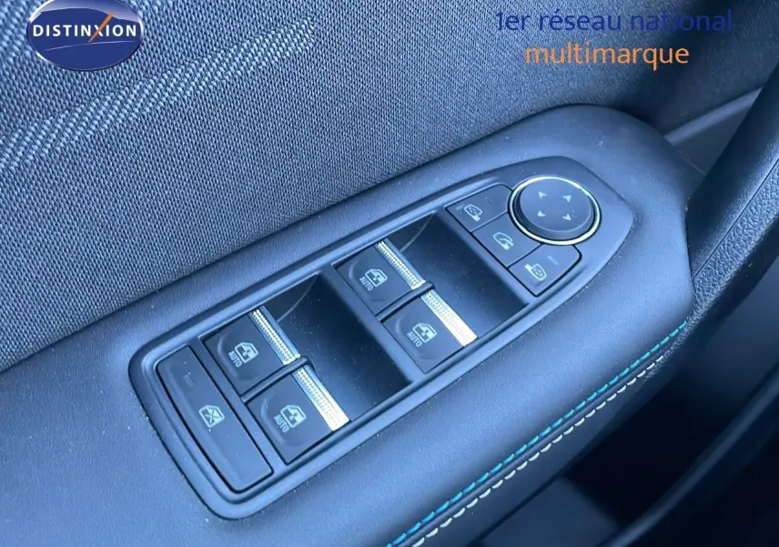 Gros plan sur les commandes des vitres électriques côté conducteur avec surpiqûres bleues dans une Renault Symbioz bleu iron metal.