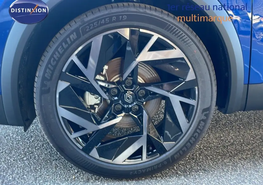 Gros plan sur la roue avant droite bleu iron metal d’une Renault Symbioz 1.6 E-Tech hybride avec jante noire et argentée.