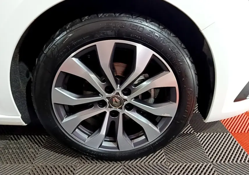 Gros plan sur la roue avant gauche de la Renault Mégane blanche 2023 avec jante alliage à plusieurs branches.