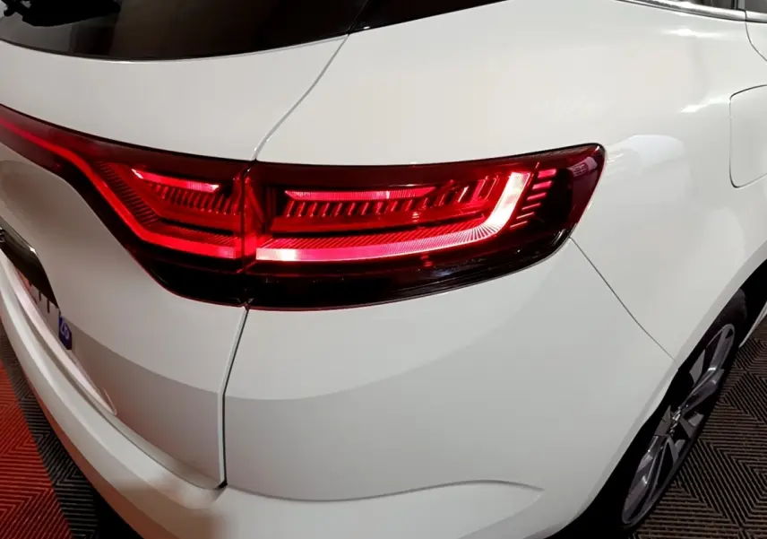 Gros plan sur le feu arrière droit rouge d'une Renault Mégane blanche, vue arrière en intérieur.