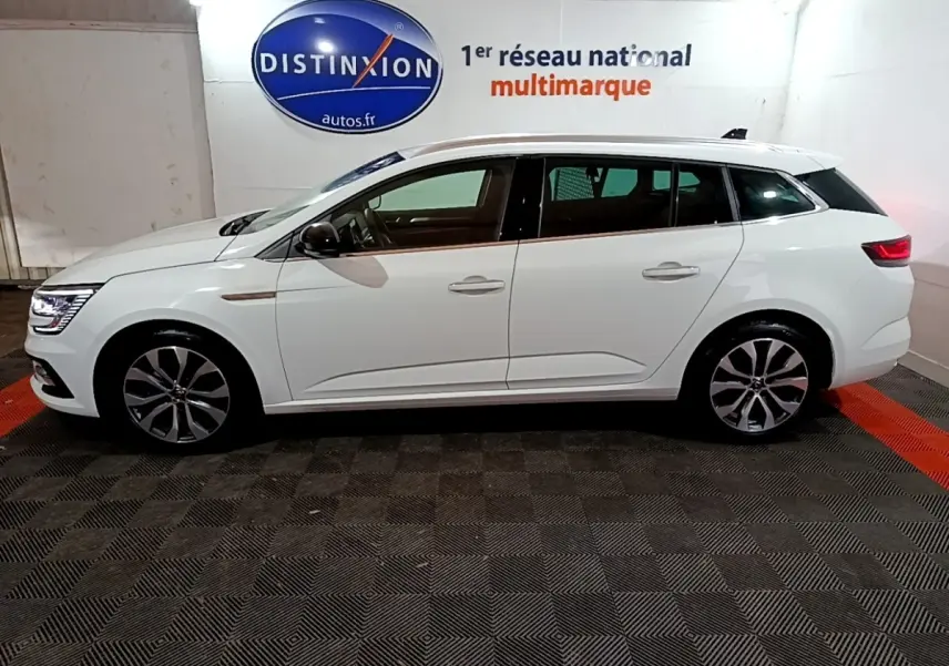 Profil côté gauche d'une Renault Mégane Techno TCe 140 EDC blanche, avec jantes alliage et feux LED visibles.