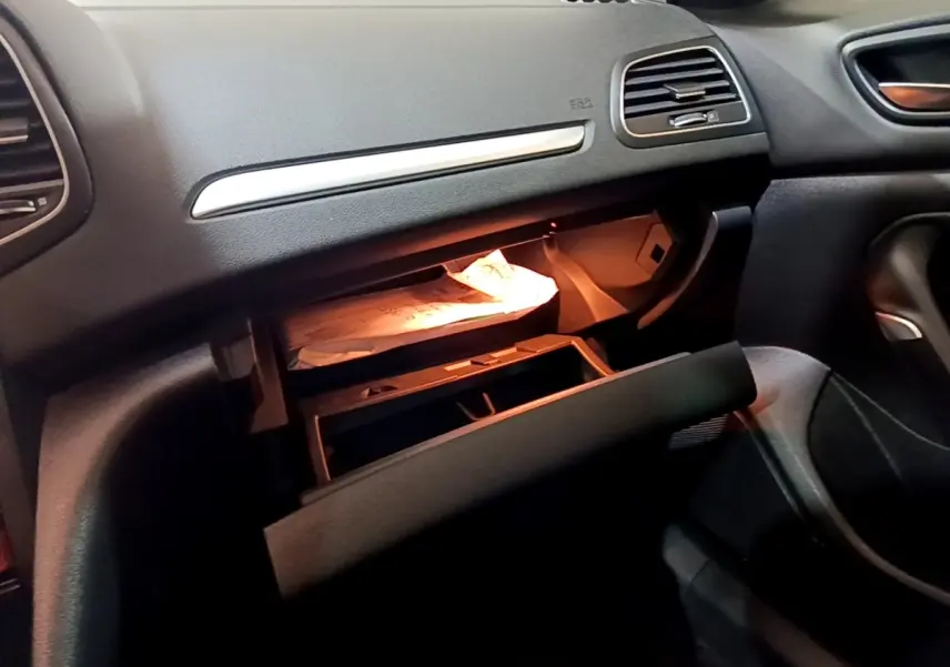 Intérieur de la Renault Mégane Techno TCe 140 2023, vue du côté passager avec boîte à gants ouverte et éclairage intérieur.