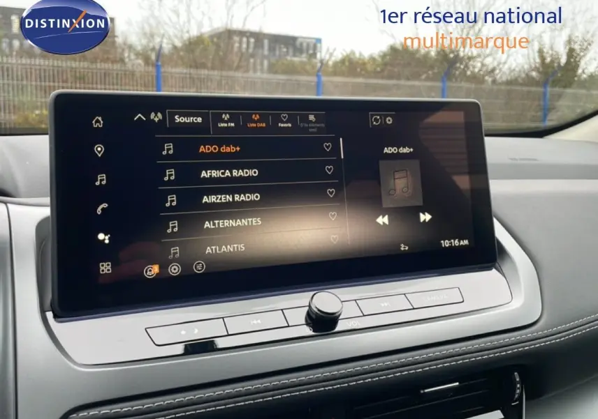 Écran tactile central du Nissan Qashqai 1.5 E-POWER 2025 affichant les stations radio, intérieur gris clair avec coutures blanches.