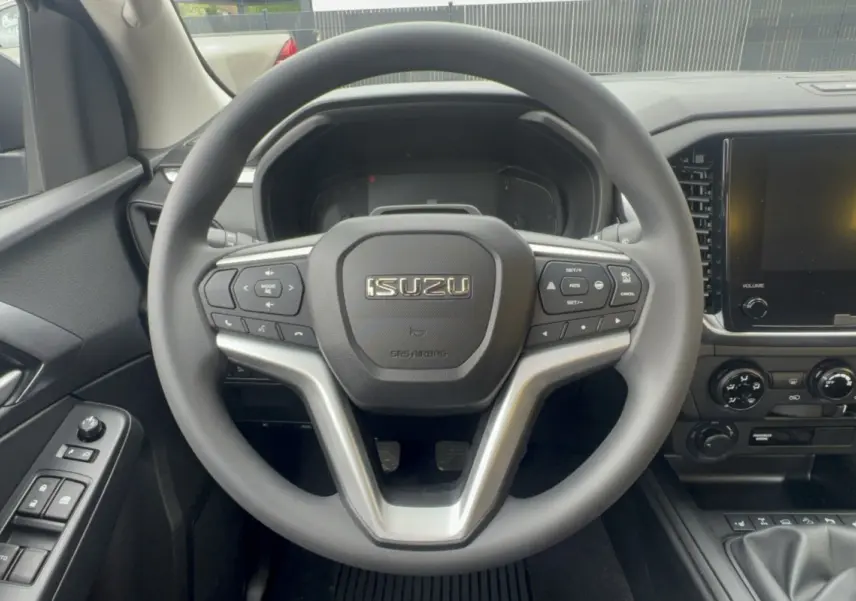Vue centrée sur le volant multifonctions noir de l'Isuzu D-MAX 2026 avec tableau de bord et écran tactile visibles.