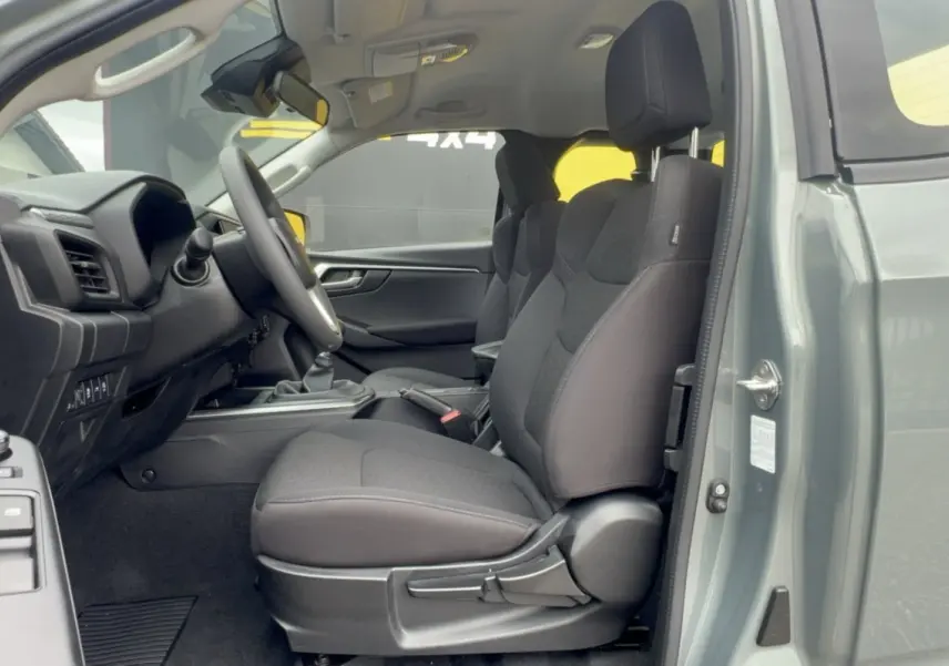 Vue intérieure côté conducteur de l'Isuzu D-MAX 2026 vert Inishmore, sièges tissu noirs et tableau de bord moderne.