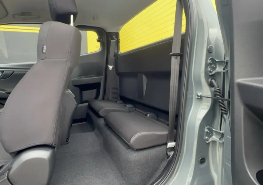 Vue intérieure côté droit du pick-up Isuzu D-MAX 2026 Inishmore green, montrant la banquette arrière et la porte ouverte.