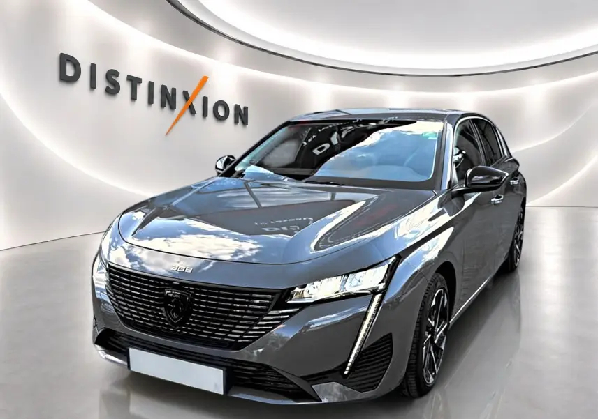 Vue 3/4 avant d'une Peugeot 308 gris selenium avec calandre noire et feux LED verticaux, en showroom lumineux.