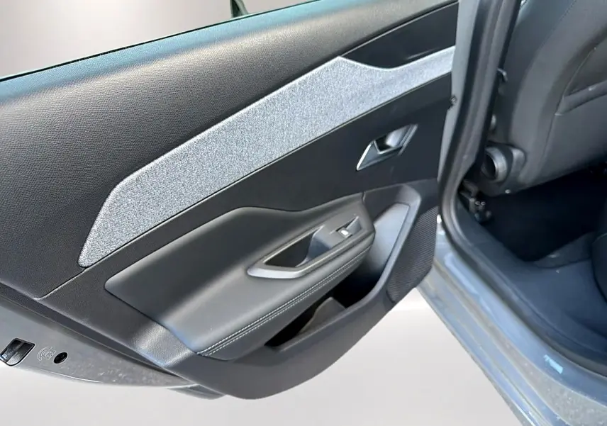 Vue rapprochée de la porte arrière gauche grise selenium de la Peugeot 308 2025 avec habillage tissu clair et commandes de vitre.