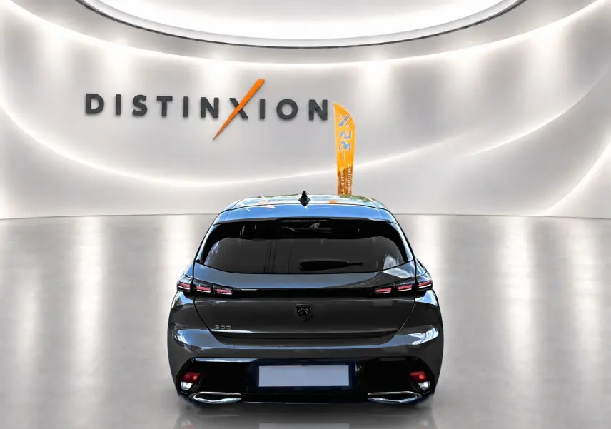 Vue arrière d'une Peugeot 308 gris selenium 2025 dans un showroom lumineux avec logo Distinxion en arrière-plan.