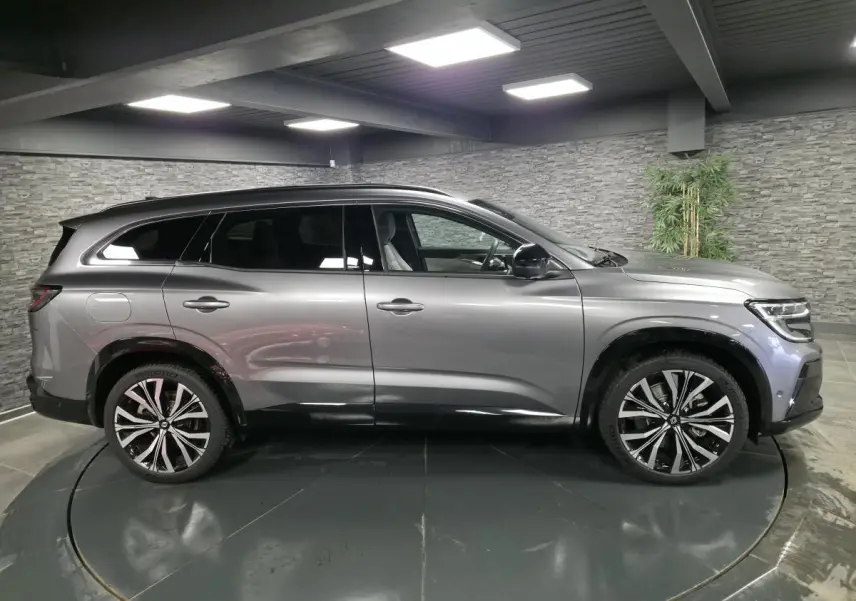 Profil droit du Renault Espace gris Baltique 2025 avec jantes alliage 20 pouces et barres de toit noir matifié.