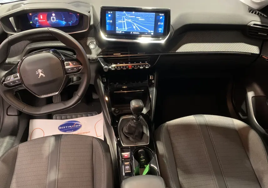 Vue intérieure avant de la Peugeot 208 PureTech 100 Allure Business gris, avec tableau de bord numérique et écran GPS central.