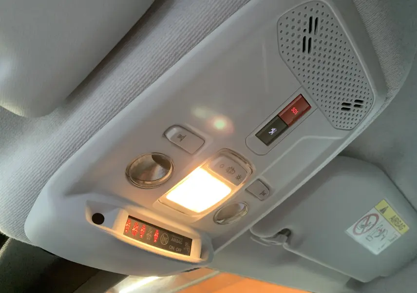Vue intérieure en plongée du plafonnier gris clair avec éclairage et boutons SOS dans une Peugeot 208 2021.