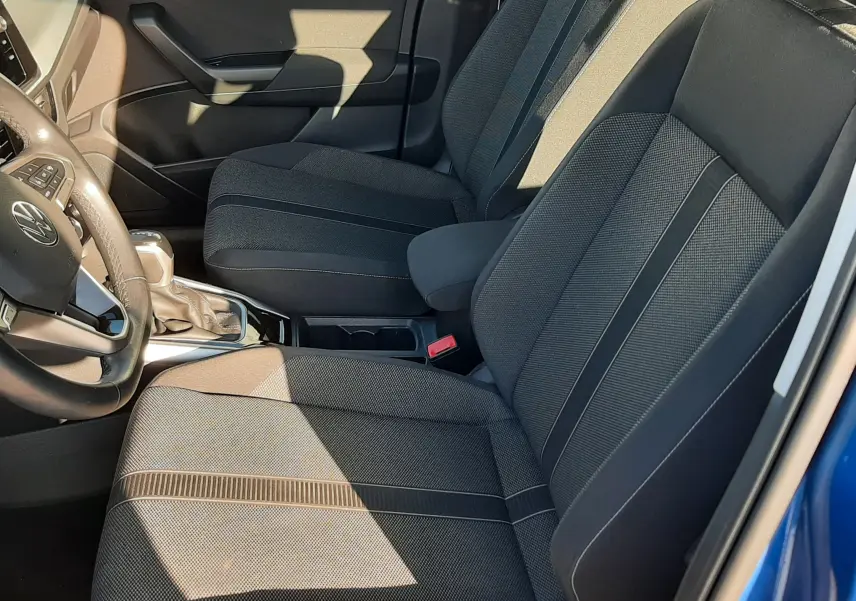 Vue intérieure côté conducteur du Volkswagen T-Roc bleu 2022, mettant en valeur les sièges en tissu gris foncé et la console centrale.