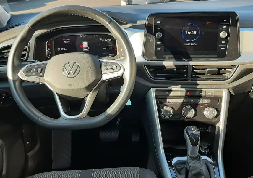 Vue intérieure du tableau de bord du Volkswagen T-Roc 2022, avec volant multifonction et écran tactile central allumé.