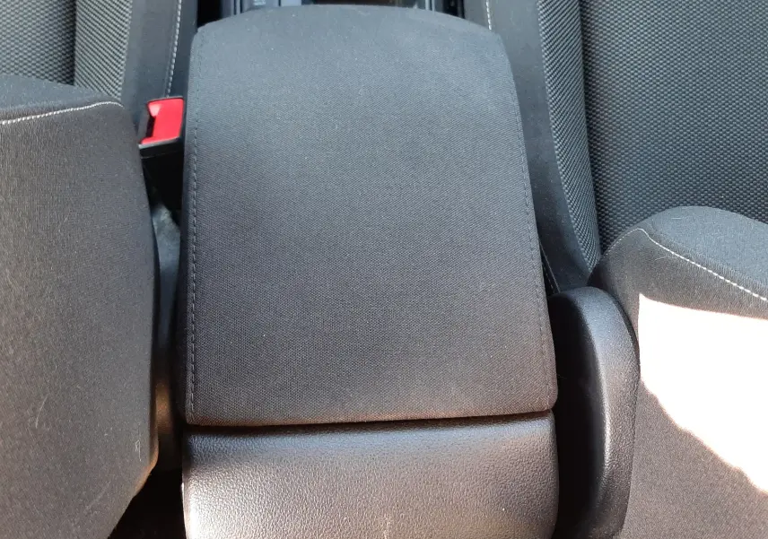 Vue plongeante sur l'accoudoir central tissu gris entre les sièges avant du Volkswagen T-Roc 1.5 TSI bleu 2022.