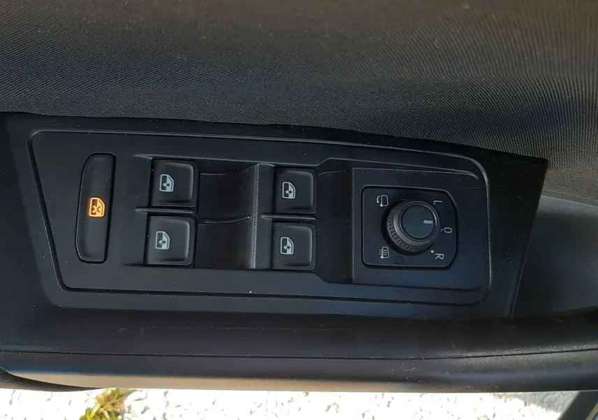 Gros plan sur les commandes de lève-vitres et réglage des rétroviseurs côté conducteur du Volkswagen T-Roc bleu 2022.