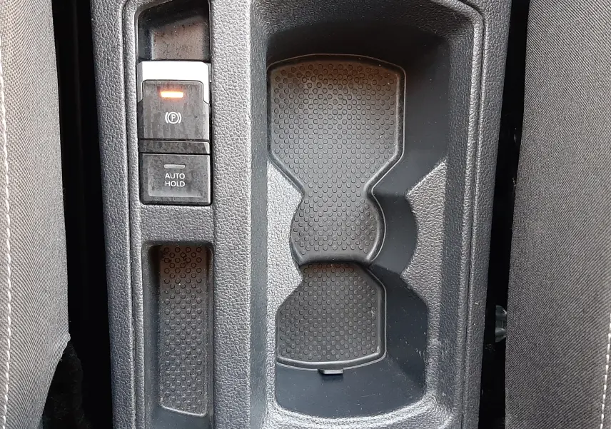 Gros plan sur la console centrale du Volkswagen T-Roc 1.5 TSI 2022, montrant le frein à main électrique et porte-gobelets.