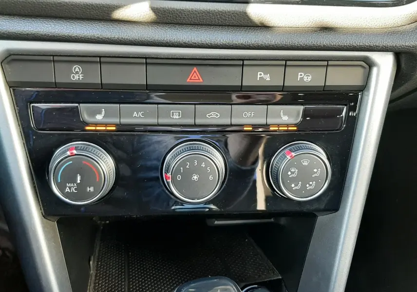 Vue rapprochée de la console centrale du Volkswagen T-Roc bleu 2022, montrant les commandes de climatisation et le levier de boîte automatique.