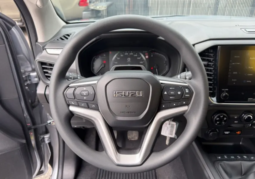 Vue centrée sur le volant multifonctions noir d’un Isuzu D-MAX 2026 avec tableau de bord et écran tactile visibles.