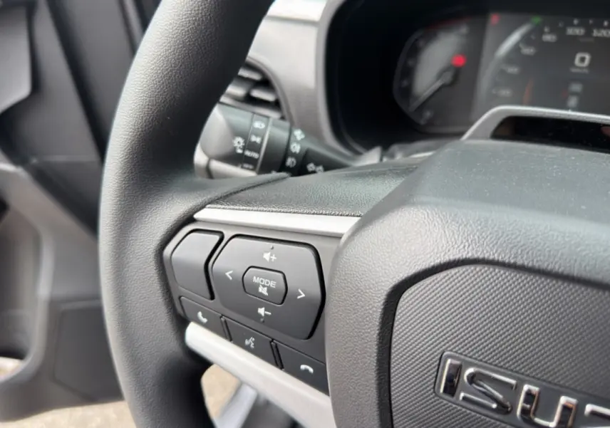 Gros plan sur le volant multifonctions noir de l'Isuzu D-MAX 2026, avec commandes audio et téléphone intégrées.