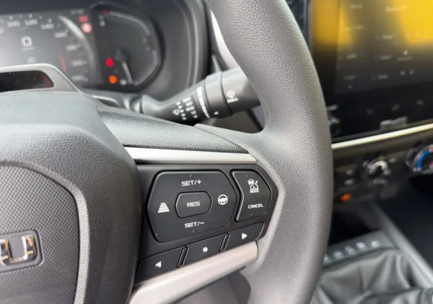 Gros plan sur le volant multifonctions gris du pick-up Isuzu D-MAX 2026 avec commandes de régulateur et tableau de bord flou.