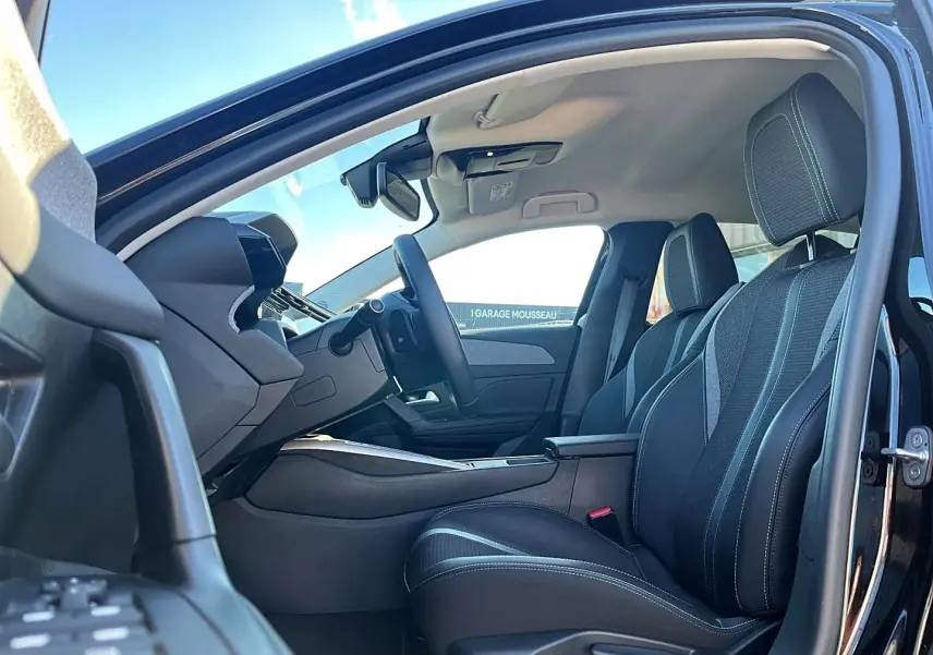 Vue intérieure côté conducteur de la Peugeot 308 noire 2025, mettant en valeur les sièges et le tableau de bord moderne.