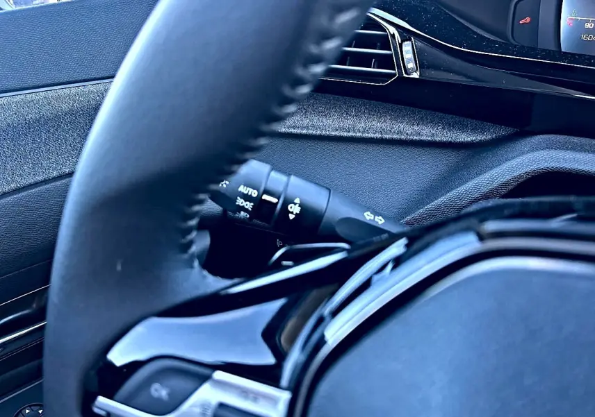 Gros plan sur le volant noir multifonction et la commande des phares de la Peugeot 308 1.5 BlueHDi 130 Allure EAT8.
