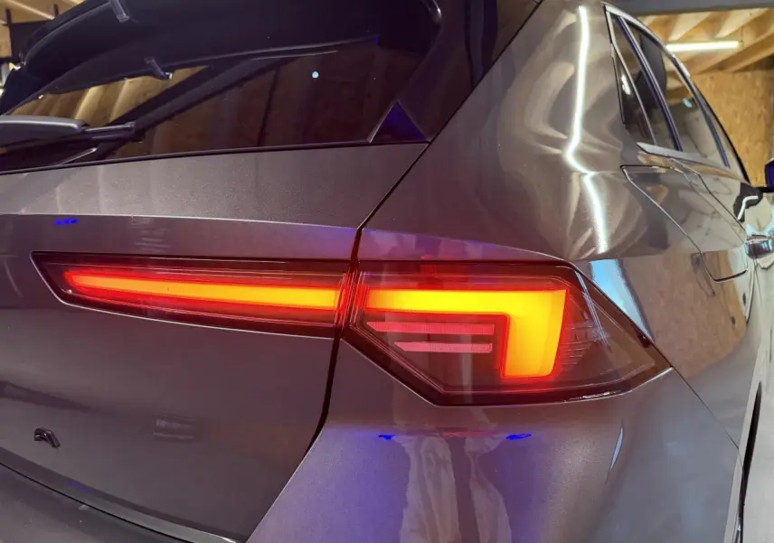 Gros plan sur le feu arrière droit d’une Opel Astra gris foncé, soulignant les lignes modernes et le vitrage surteinté.