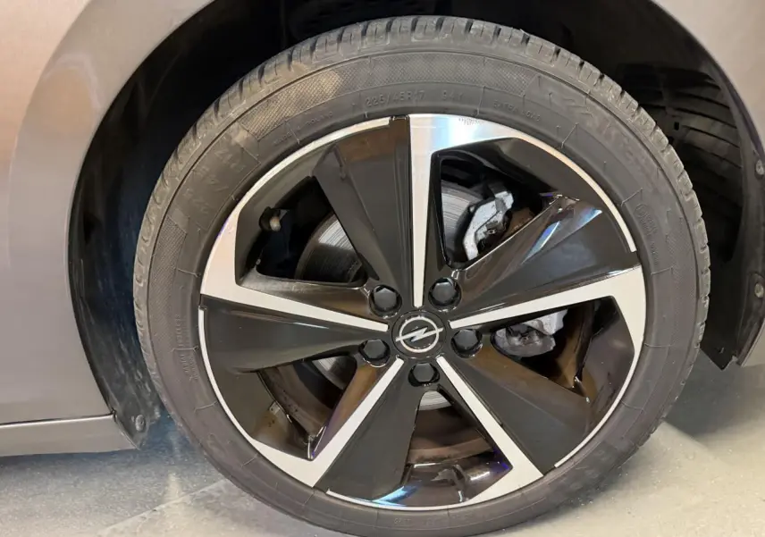 Gros plan sur la jante alliage 17 pouces noir et argent de l’Opel Astra gris foncé, avec logo Opel central.